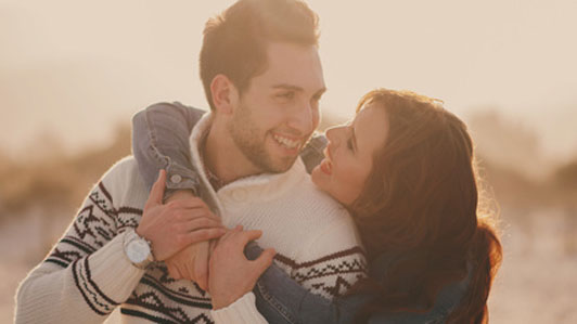 woman hugging man in sweater outdoors