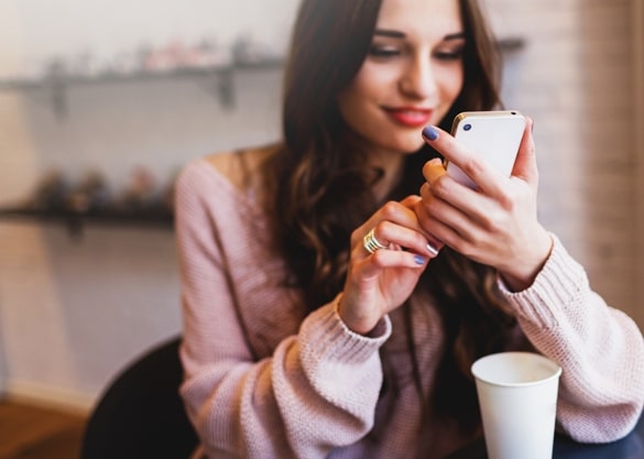 Woman typing write message on smart phone in a modern cafe - Attracting a Taurus man through texts